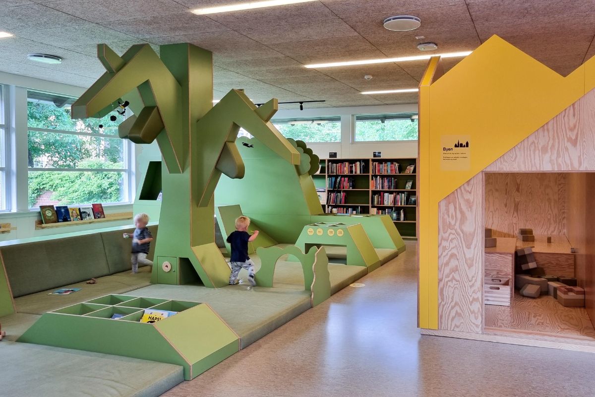 Kaksi lasta leikkimässä Roskilden kirjaston lastenosaston puisissa pehmustetuissa rakennelmissa.